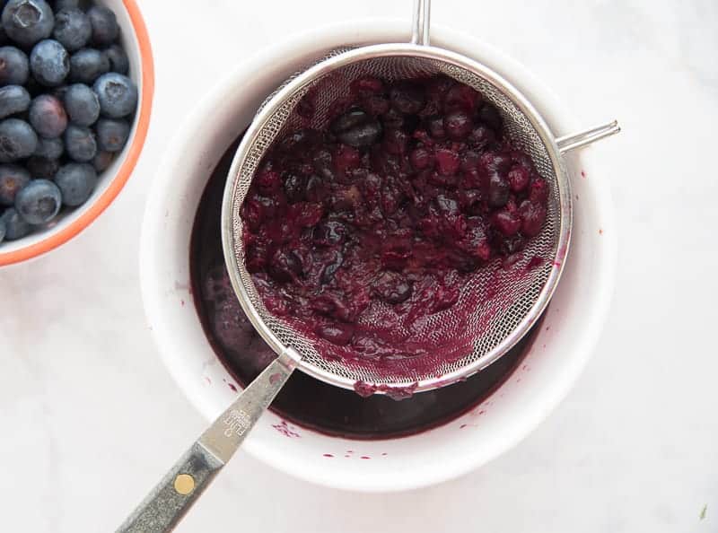 The blueberries are pressed into a strainer to extract the juice