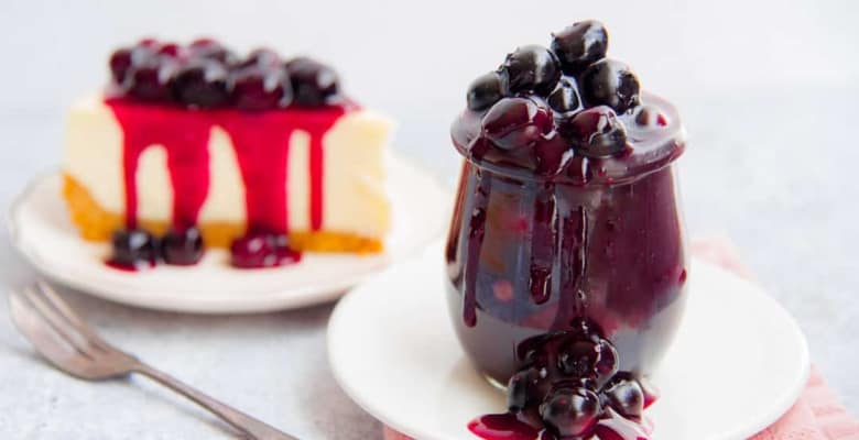 A jar of Blueberry Ginger Dessert Topping sits on a white plate