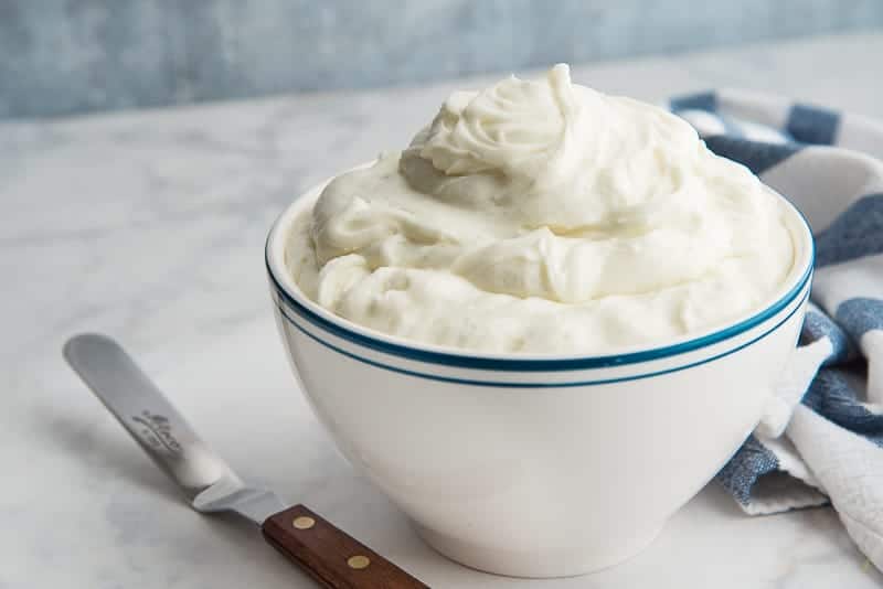 A white bowl with a blue rimmed filled with Cream Cheese Frosting