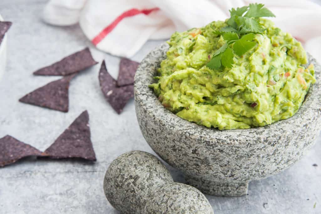 A close-up image of a molcajete filled with Chunky Guacamole