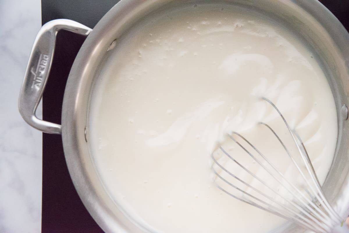 The milk is thickened and whisked in a stainless steel pot