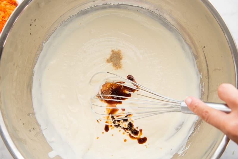 Soy sauce and white pepper are added to the mayonnaise mixture. A whisk is ready to blend them into the dressing