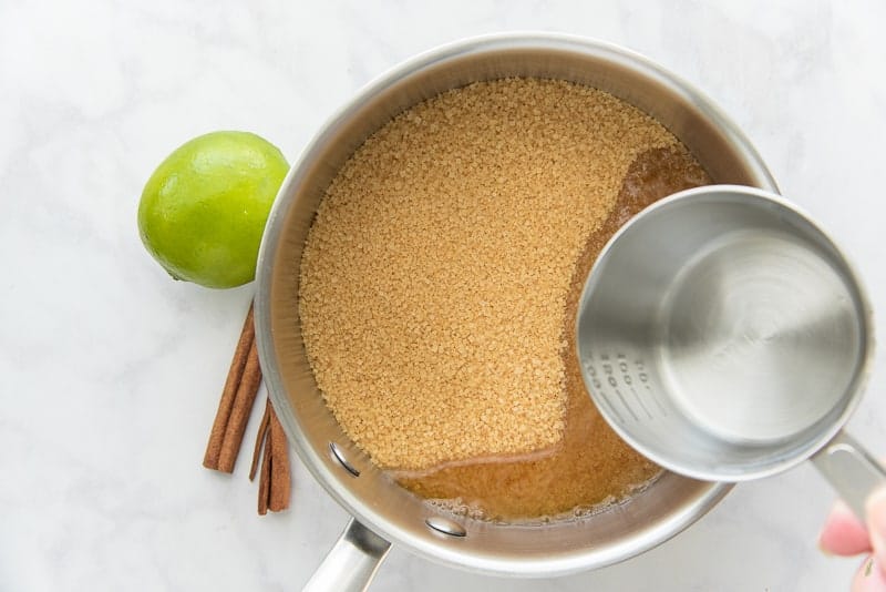 Water is added to a pot filled with raw cane sugar to make simple syrup which will sweeten the Agua de Jamaica
