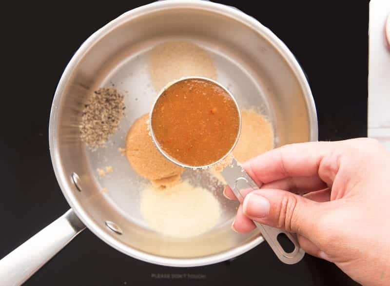 Hot sauce is added to spices in a silver pot