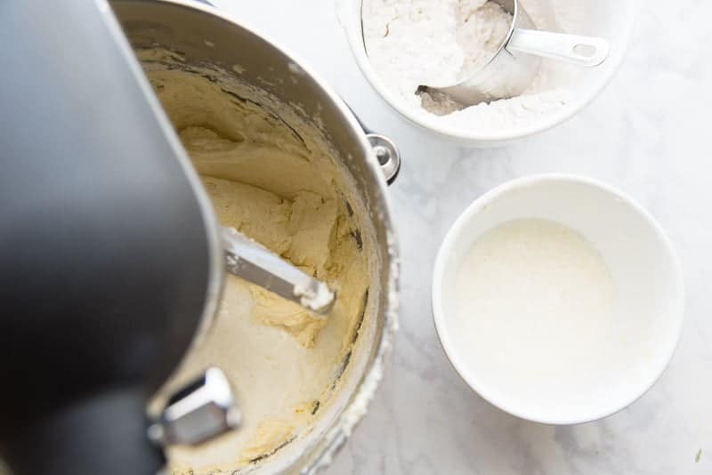 A sour cream and 7up mixture is added to the bowl of a stand mixer after flour is added