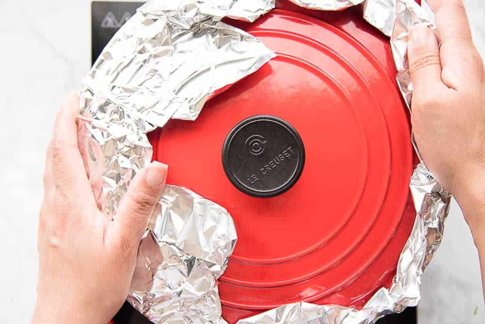 Aluminum foil is placed between the lid and the pot to create a tight seal so the rice can steam perfectly.