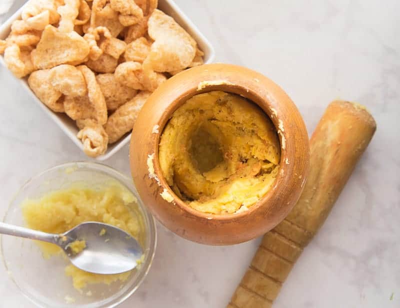The plantains, garlic, and pork rinds are mashed together in a wooden mortar and pestle.