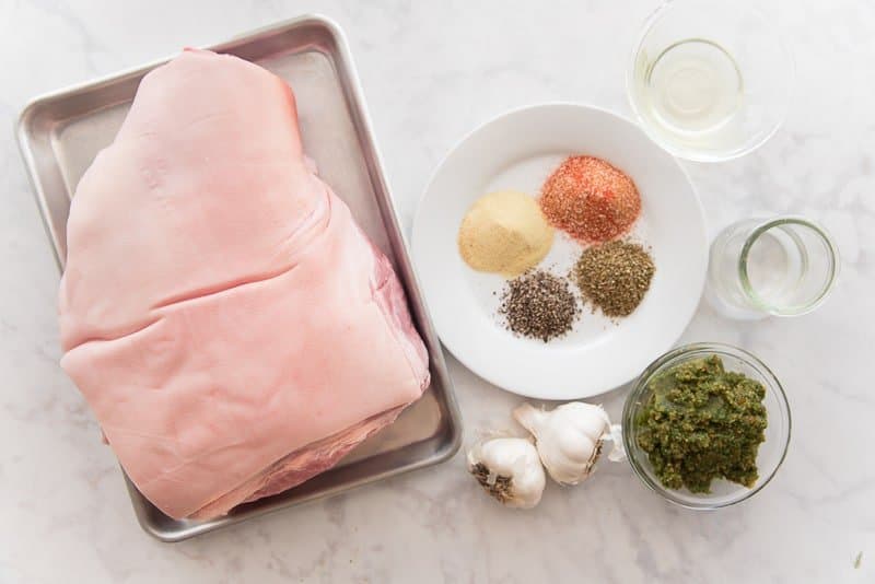 The ingredients for pernil: a pork shoulder, spices, white vinegar, sofrito, and fresh garlic.