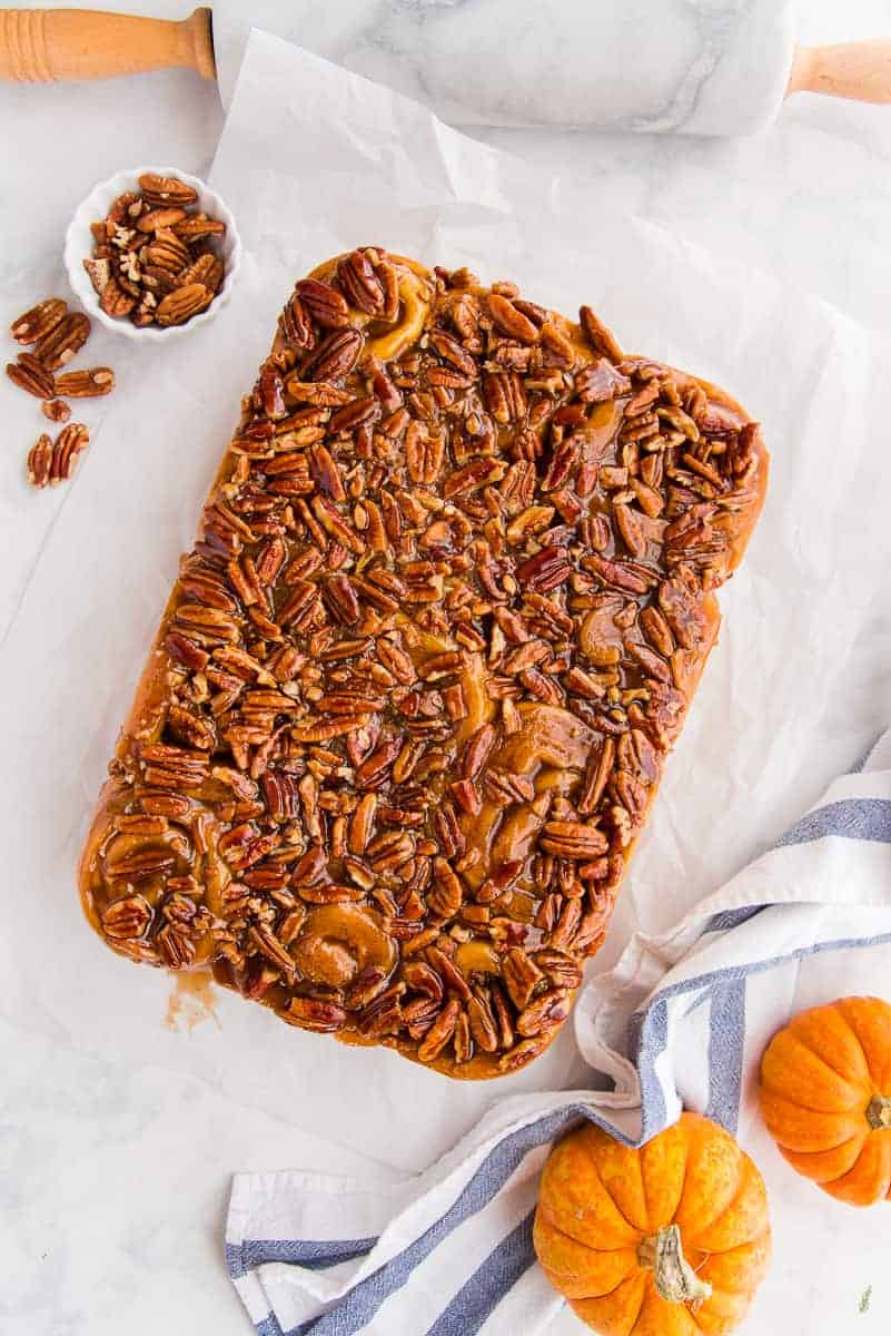 The Pumpkin Caramel Sticky Buns are turned onto a sheet of parchment to display the caramel pecan topping.