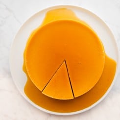 Orange whole flan with a piece cut on a white plate
