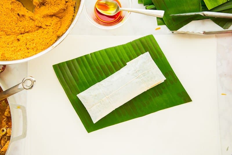 Pasteles, wrapped in white paper and tied in a bundle on a green banana leaf