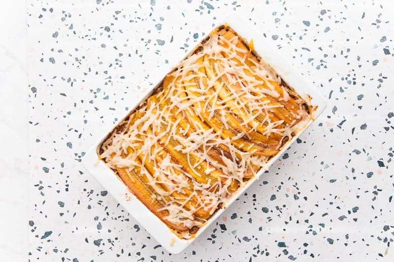 The baked vegan pastelón is on a terrazzo surface,