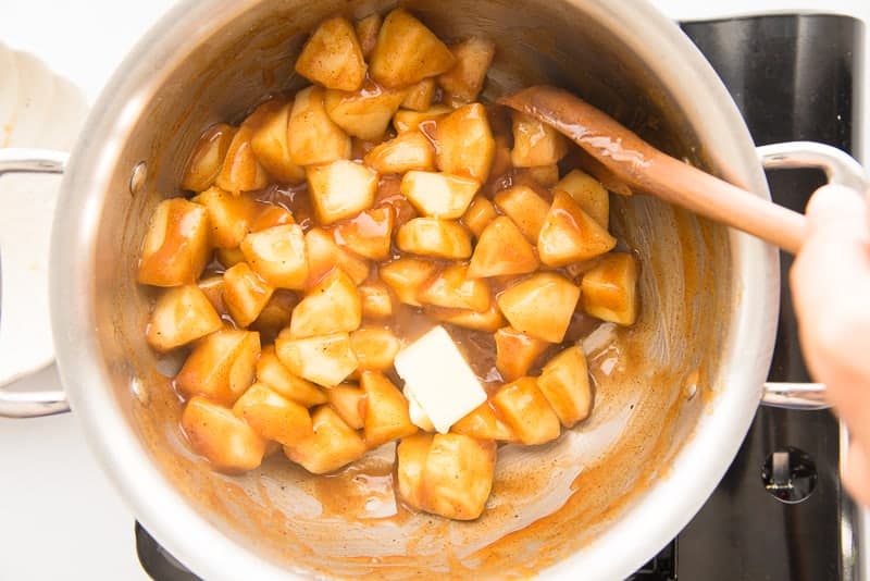 Butter is stirred into the apple pie topping in a silver pot