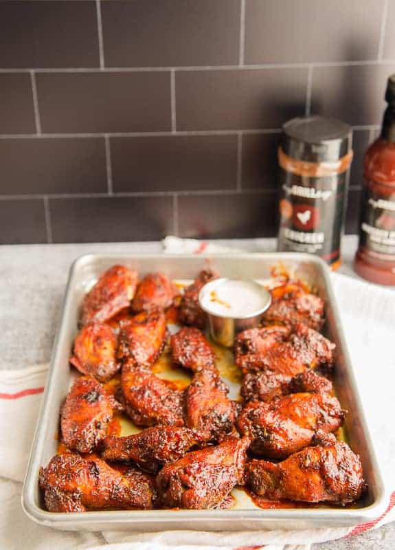 The air fried Guava BBQ wings are on a silver sheetpan in front of a black tiled backsplash