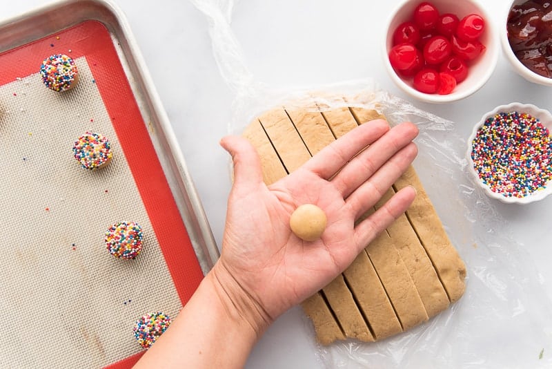 A hand holds a ball of cookie dough.