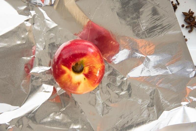 A cored apple is placed on a sheet of aluminum foil prior to being wrapped and baked.