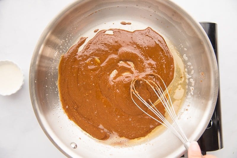 The caramel is stirred with a silver whisk