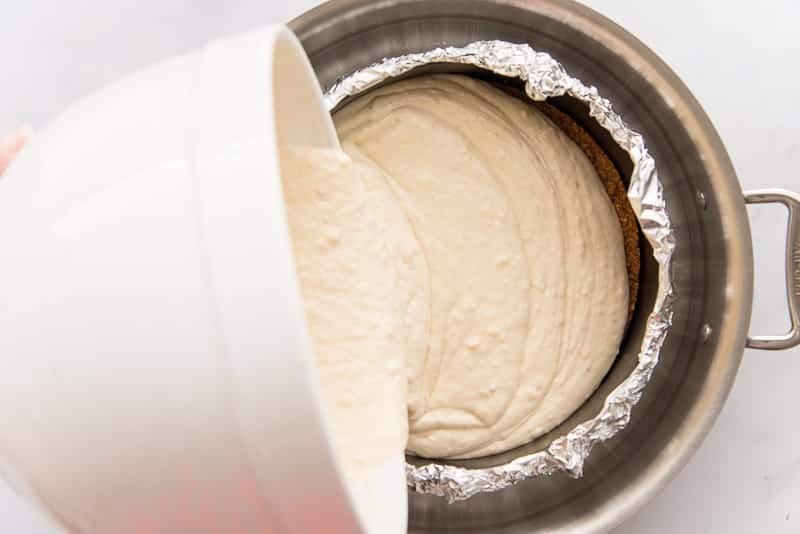 The banana cheesecake batter is poured into a foil-wrapped cheesecake pan.