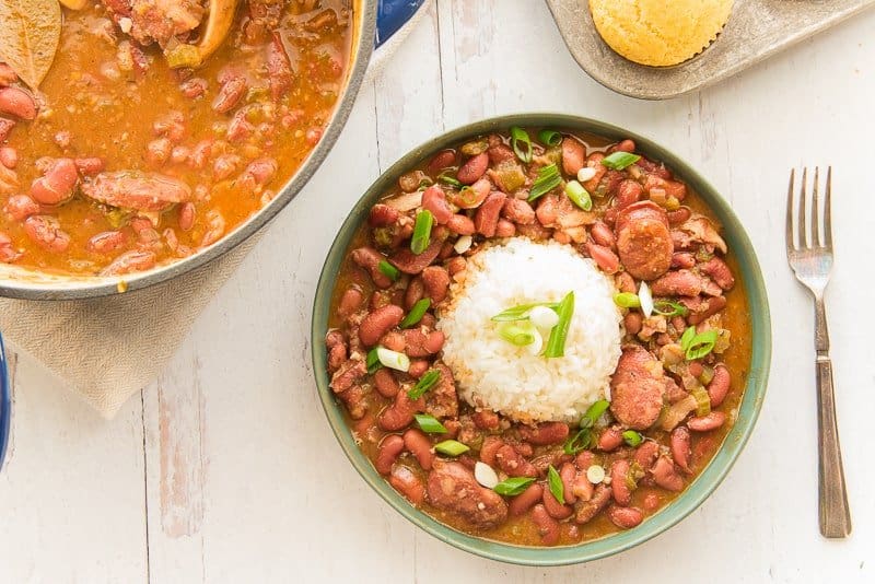 Overhead image of a green bowl of Creole red beans and rice with a silver fork on right of bowl
