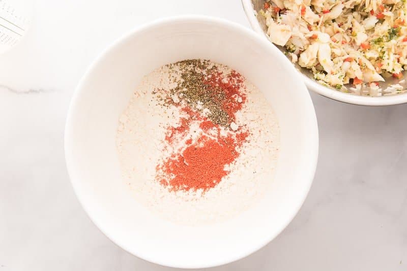 Spices are added to the flour in a white mixing bowl