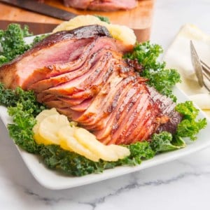 Preview image of Ham with Spiced Brown Sugar Pineapple Glaze on a bed of kale surrounded by sliced pineapples