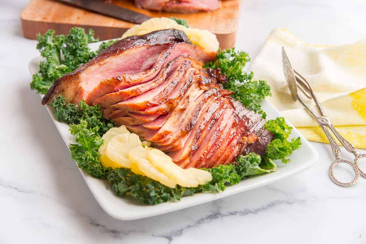 Preview image of Ham with Spiced Brown Sugar Pineapple Glaze on a bed of kale surrounded by sliced pineapples