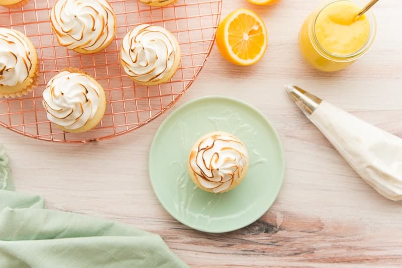 Toasted meringue on a Lemon Meringue Cupcake which is on a green plate.