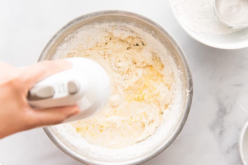 Flour and milk are added to the batter in a silver bowl.