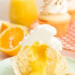 Portrait image of a cut Lemon Meringue Cupcake reveals the lemon ucrd filling.