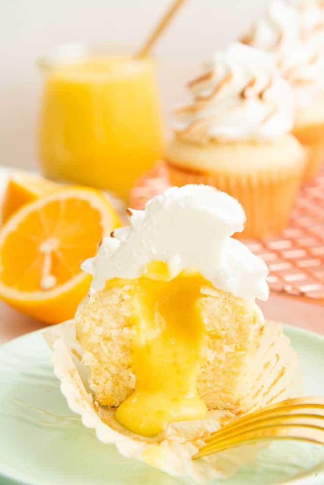 Portrait image of a cut Lemon Meringue Cupcake reveals the lemon curd filling.