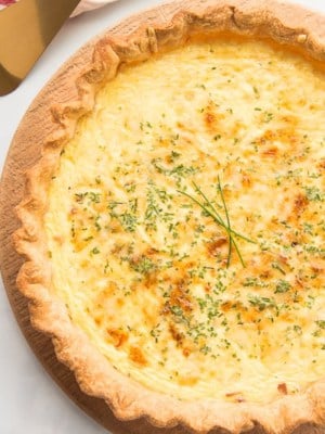 Overhead horizontal image of a baked quiche lorraine on a wooden board