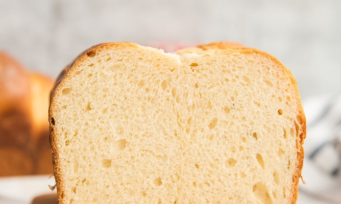Lead image of a cut loaf of Brioche Bread on a wooden board.