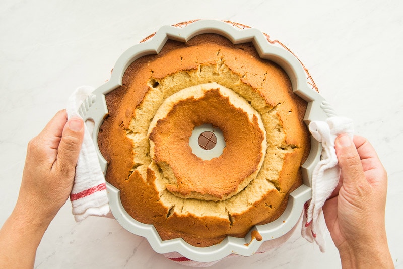 The baked pound cake in its bundt pan held by two hands.