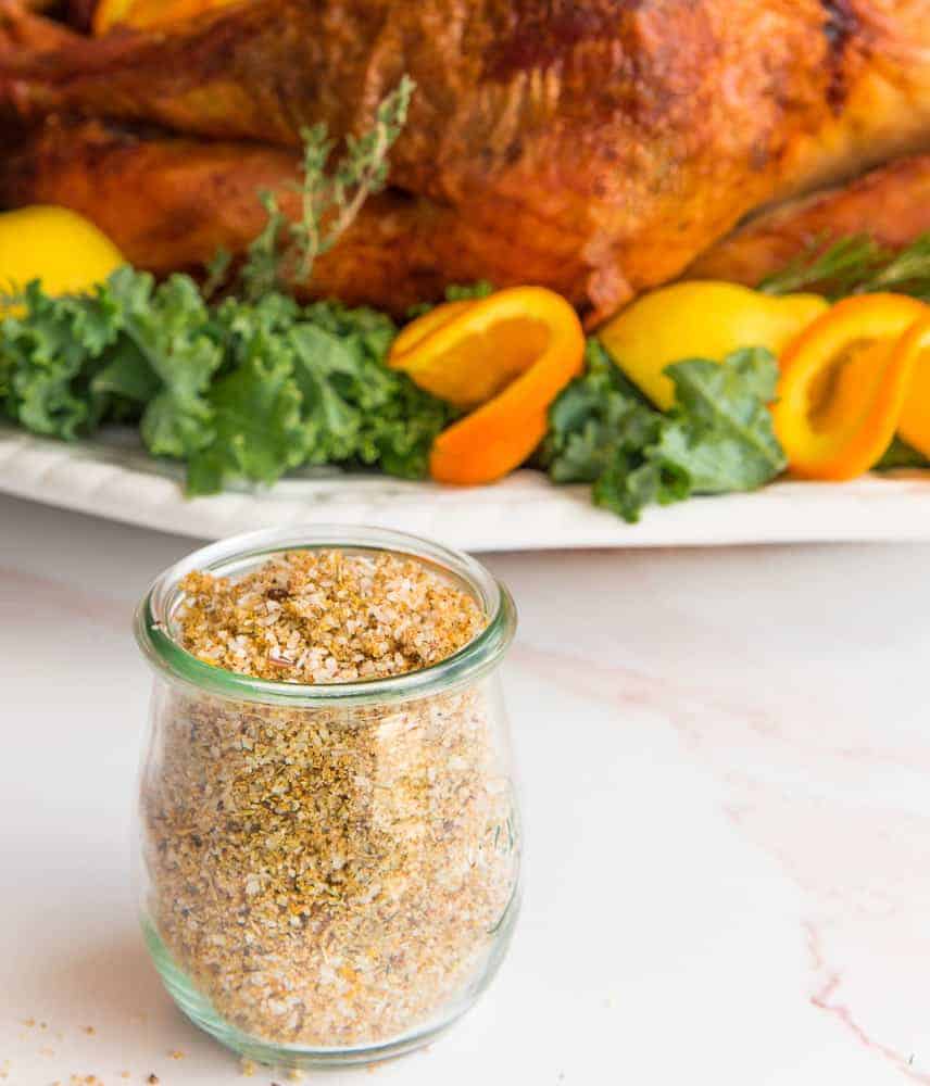 Lead image of a jar of Citrus-Herb Dry Brine in front of a roast turkey on a white platter.