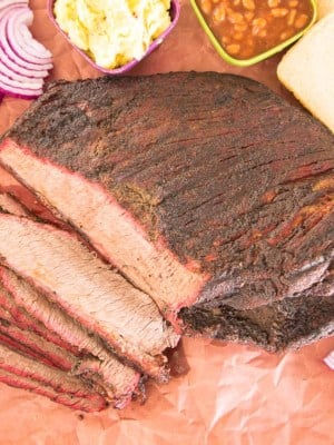 The sliced coffee-rubbed smoked brisket overhead shot surrounded by condiments and sides