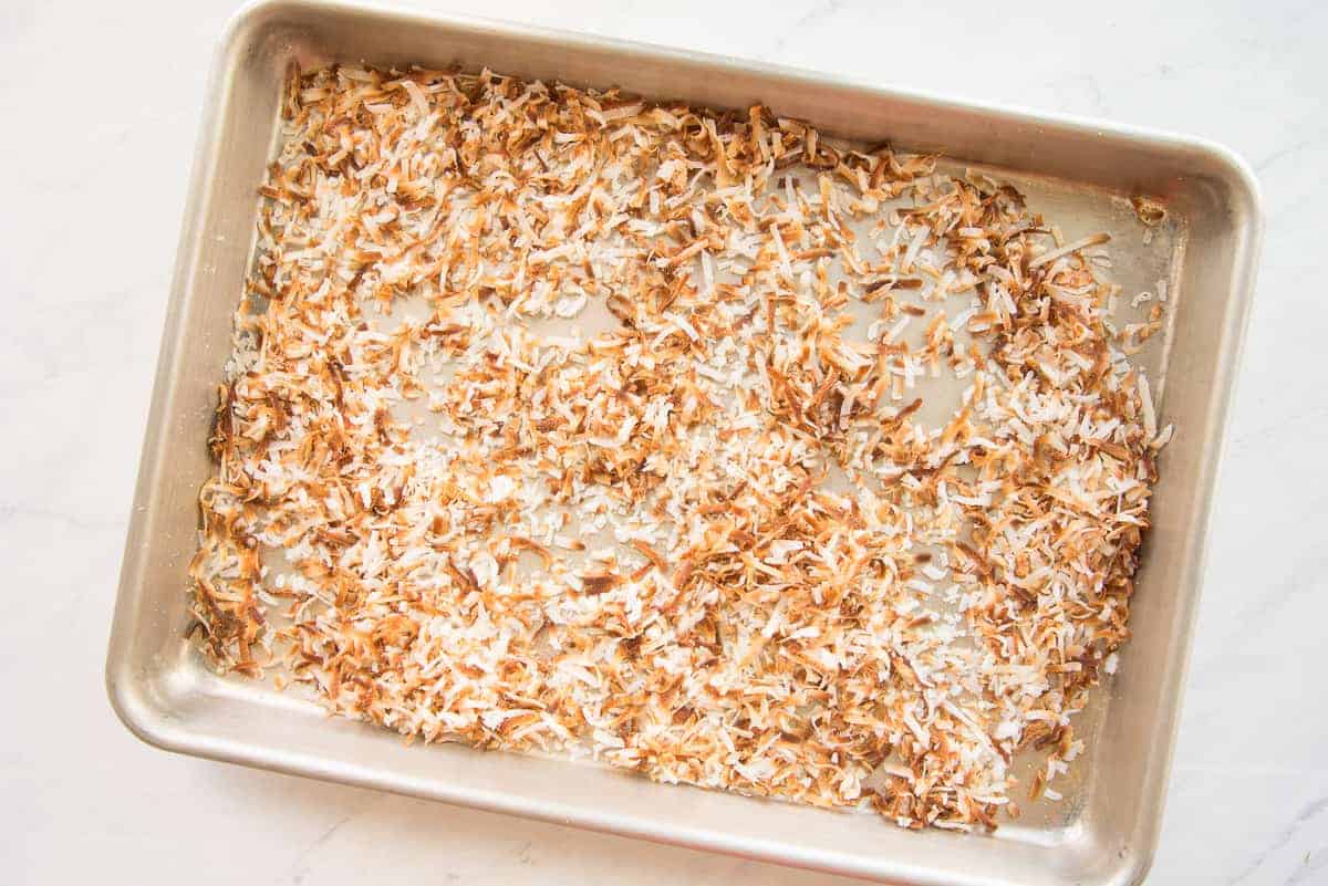 Toasted coconut flakes on a silver sheetpan