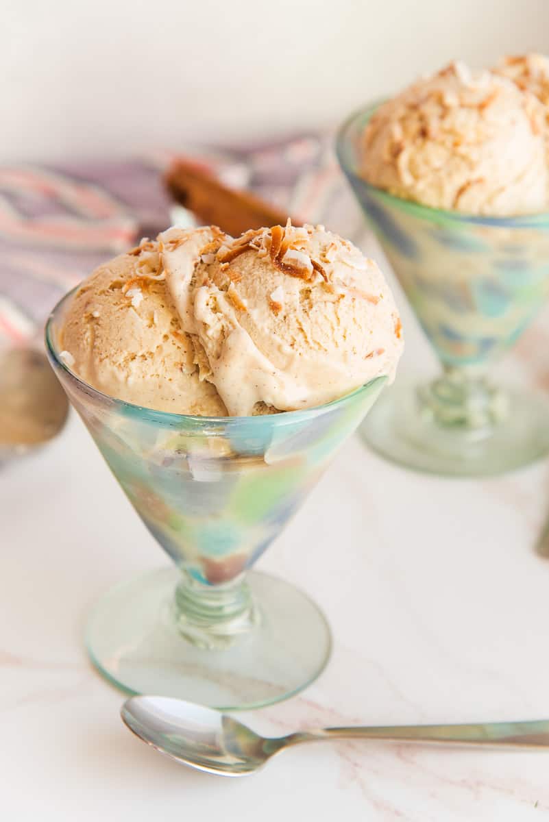 Coquito Frozen Custard in a footed green mottled ice cream dish garnished with toasted coconut flakes.