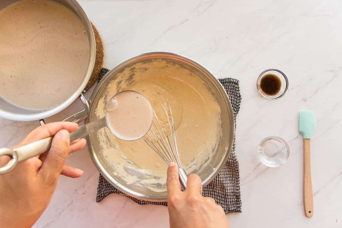 Hot coquito is ladled into the whipped egg and sugar mixture.