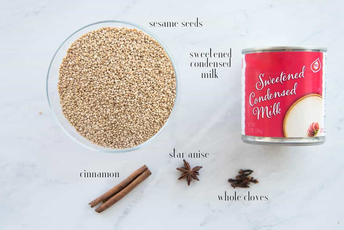 The ingredients needed to make Horchata de Ajonjolí (Sesame Seed Milk): toasted sesame seeds, sweetened condensed milk, whole cloves, star anise, and cinnamon stick.