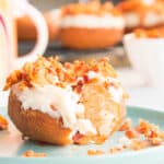 A maple bacon donut with a bite removed sits on a teal plate