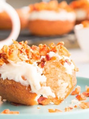 Preview image of a maple bacon donut with a bite removed on a teal plate.