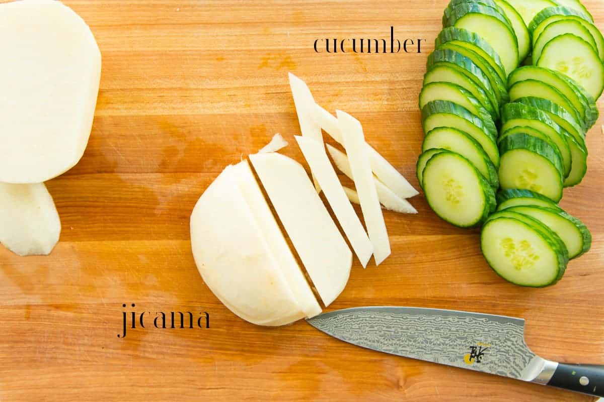 Jicama and cucumbers are sliced to add to the board.