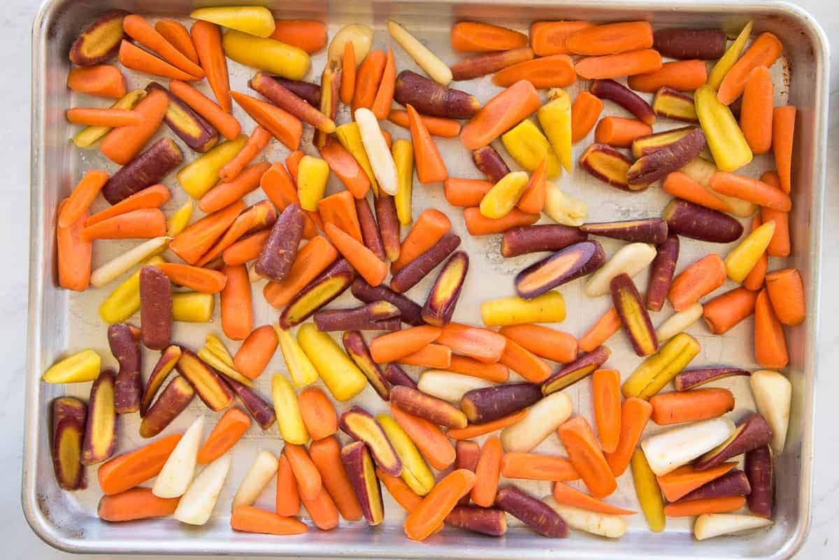 Rainbow carrots are arranged in a single layer on sheetpan.
