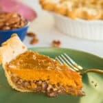 Horizontal image of a slice of Sweet Potato Maple Pecan Pie on a green plate. a gold fork rests on the plate to the right of the pie.
