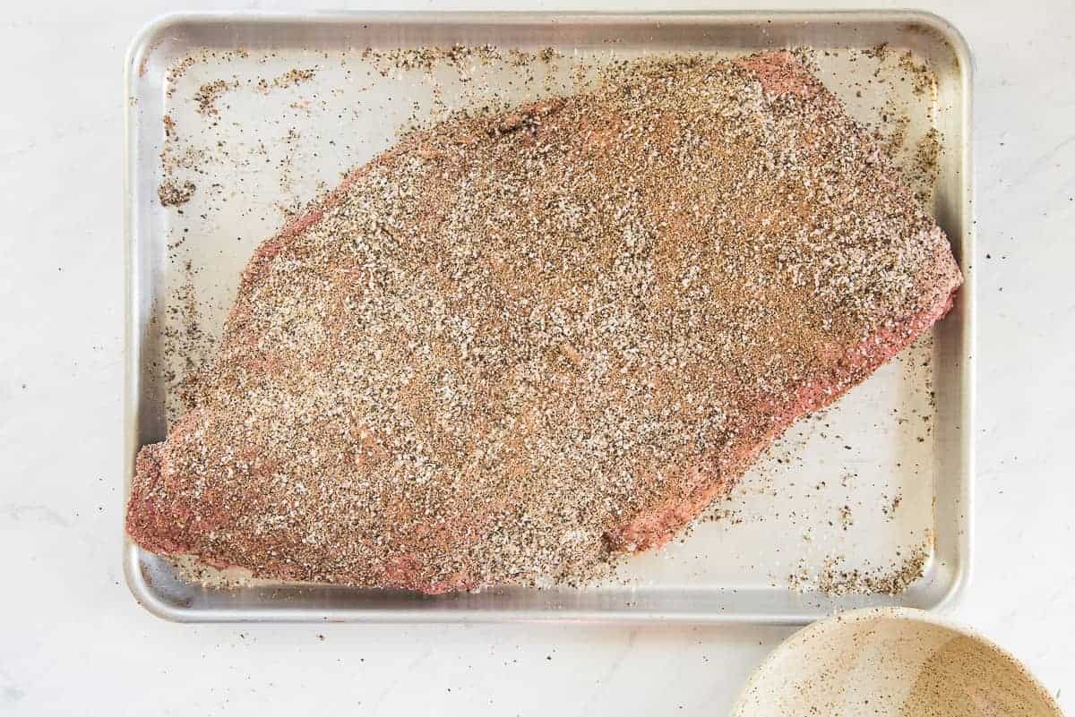 The coffee rub mixture is liberally sprinkled on the brisket.