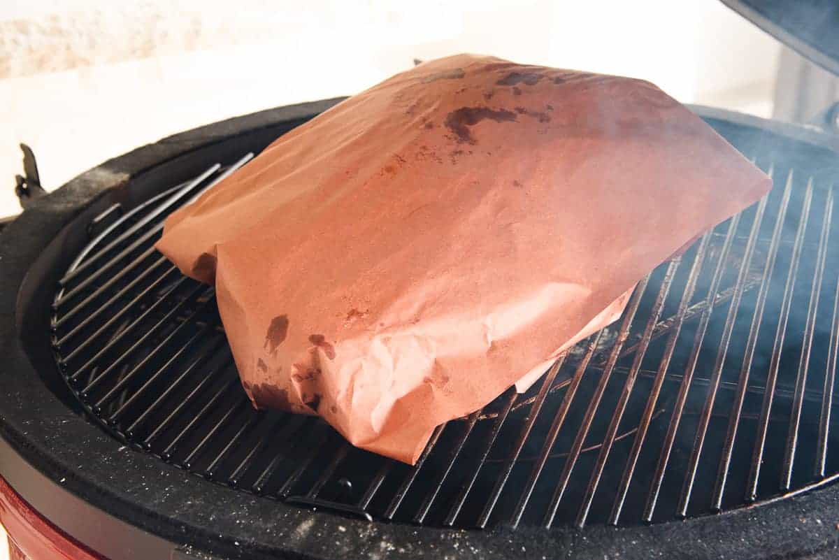 Brisket is wrapped in peach butcher paper and placed back on the smoker