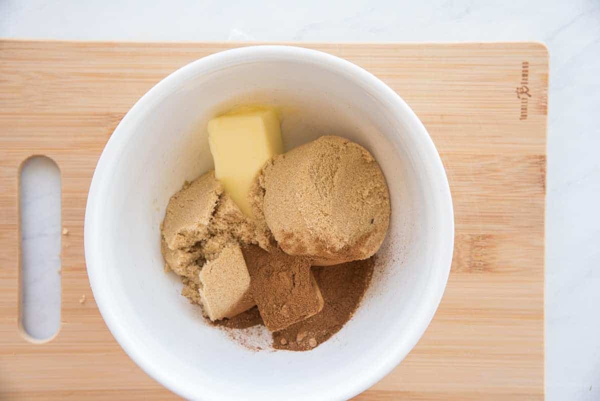 Butter, brown sugar, and spices are in a white mixing bowl