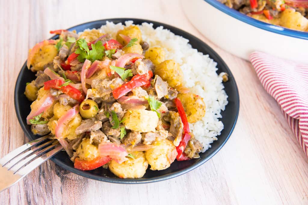 Preview image of a silver fork propped on a blue plate of Guineitos con Mollejas en Escabeche