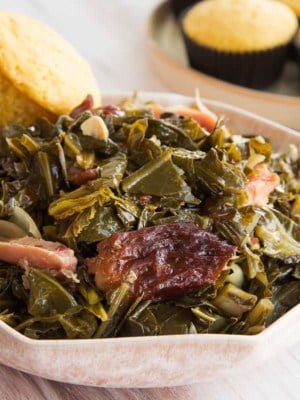 Preview image 2 of a pink bowl of Country Style Collard Greens in the slow cooker with a cornbread muffin.