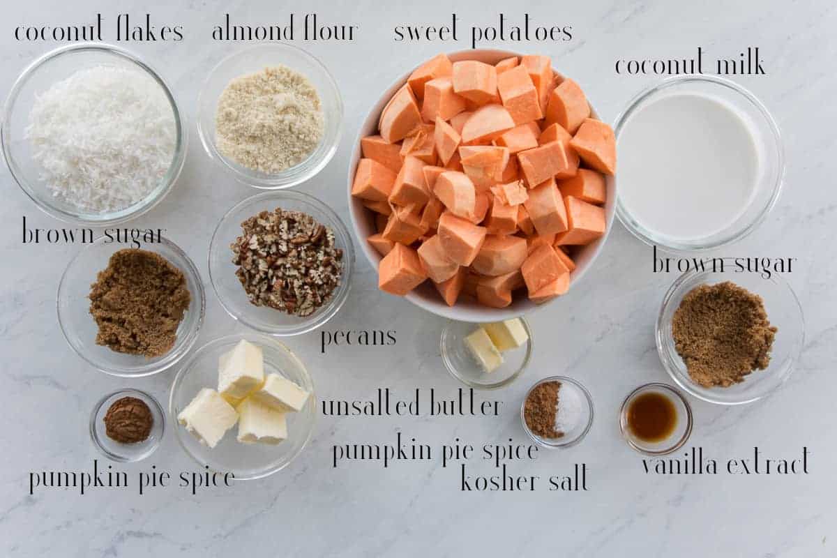The ingredients needed to make the recipe: Coconut flakes, almond flour, sweet potatoes, coconut milk, brown sugar, vanilla extract, kosher salt, pumpkin pie spice, unsalted butter, and pecans.